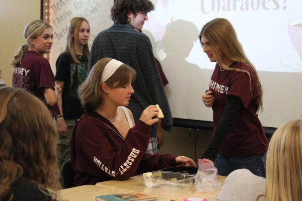 Attending the Sweet and Social Club meeting on Oct. 18, Lauren Turner and Brooke Dettner each take a cookie from the provided box in classroom D10. Photo by Gabby Robinson.