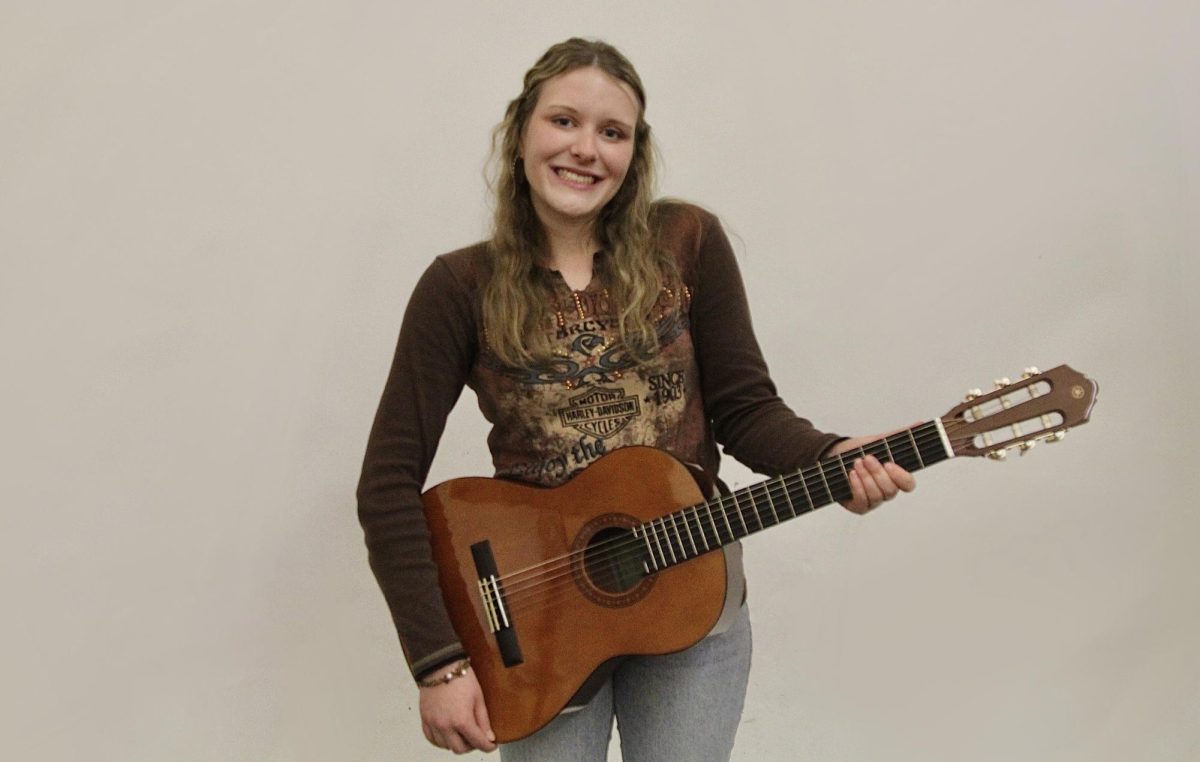 Posing with her guitar, Avery Steindorf smiles for the camera. Steindorf is a guitar player inspired by her sister, Ella Steindorf, and practices regularly. Photo by Paige Friesen.
