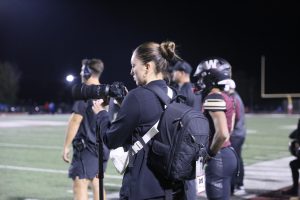 Creating content for her business, Paige Hall records a video of the varsity football team playing against Folsom Oct. 18. Photo by Emerson Kibby.