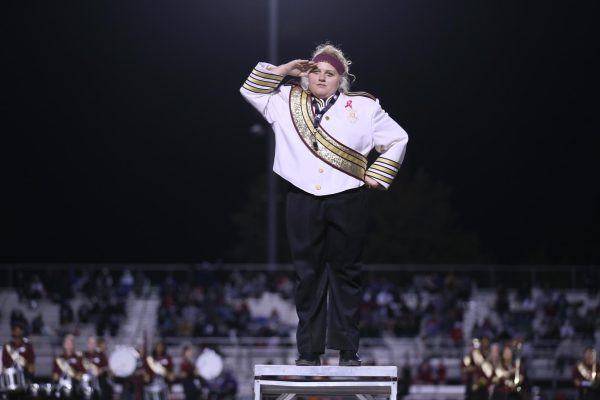 During the “Pink Out” themed football game, Lyndee Veldstra salutes the crowd before leading the band in their halftime performance Oct. 18. Photo by Emerson Kibby
