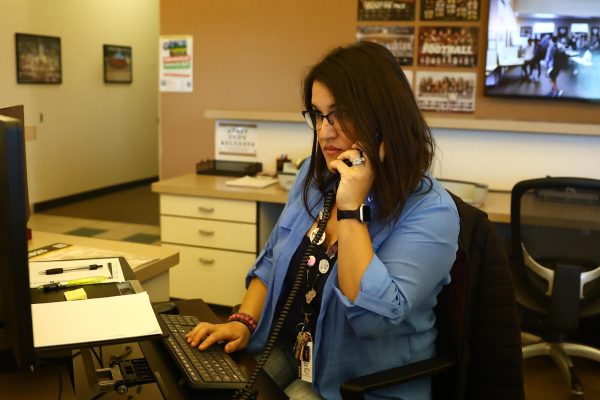 In the front office, Mrs. Jessica Alcala answers a phone call from a parent Feb. 5. After working as a discipline technician, Alcala replaced Mrs. Carmen Colhour as clerk after Colhour started as the new principal’s secretary. Photo by Desiree Montejano. 
